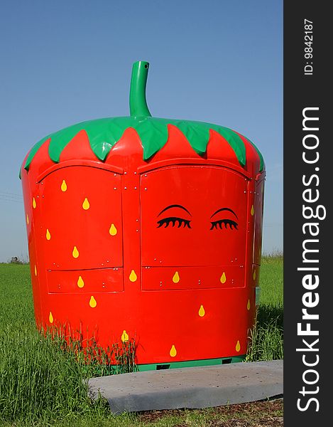 A market stand for selling strawberries photographed in the early summer sun next to a commercial acre