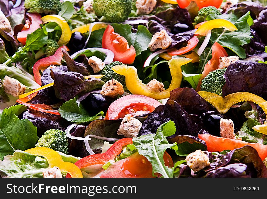 A healthy salad made up of lettuce, tomato, peppers, olives croutons and onion.