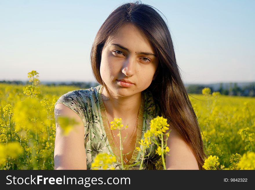 A beautiful girl standing on a field with yellow canola. A beautiful girl standing on a field with yellow canola