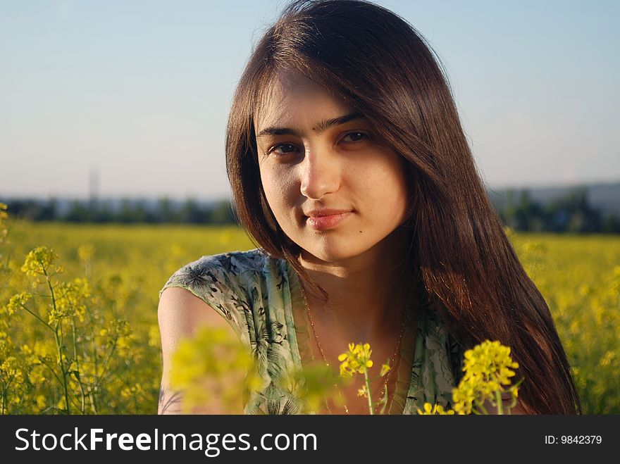 A beautiful girl standing on a field with yellow canola. A beautiful girl standing on a field with yellow canola