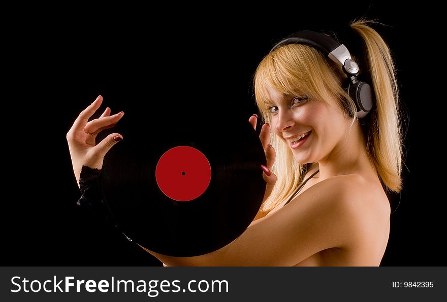 Sexual young girl with a vinyl records in hand and headphones on a black background. Sexual young girl with a vinyl records in hand and headphones on a black background