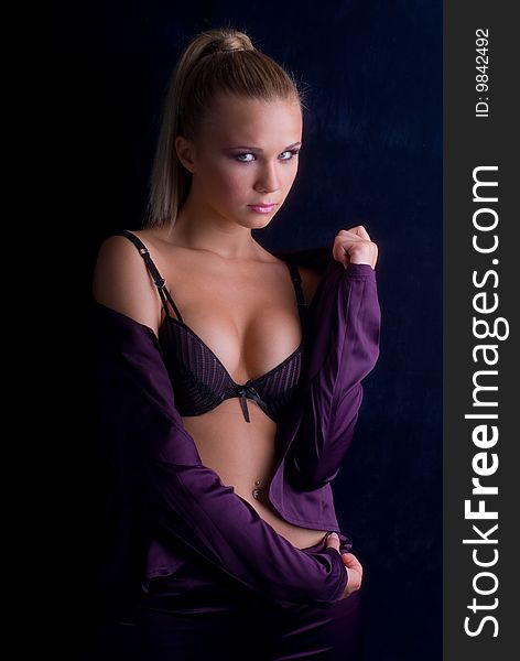 Portrait of a young beautiful girl in their underwear and lilac jacket on a black background. Portrait of a young beautiful girl in their underwear and lilac jacket on a black background