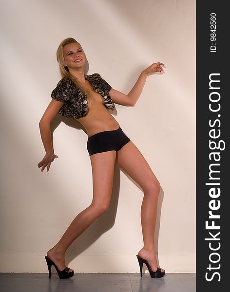 Sexual blonde in black shorts and fur bolero on a light background. Sexual blonde in black shorts and fur bolero on a light background