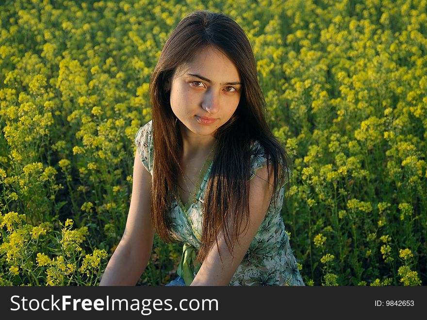 A beautiful girl standing on a field with yellow canola. A beautiful girl standing on a field with yellow canola