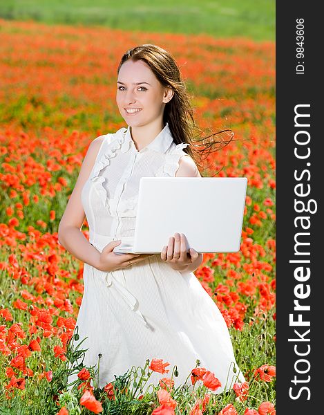Smiling girl with laptop in the poppy field