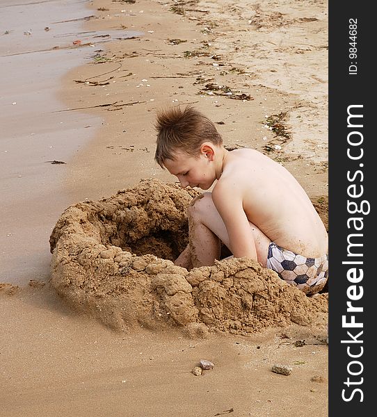 Boy building sand castle on the beach. Boy building sand castle on the beach.