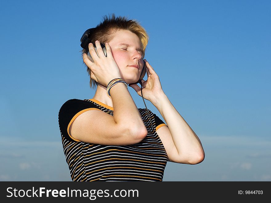 Young girl listining music on a blue sky background. Young girl listining music on a blue sky background