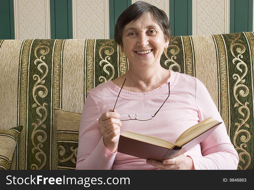 Aged woman reading a book and smiling. Aged woman reading a book and smiling