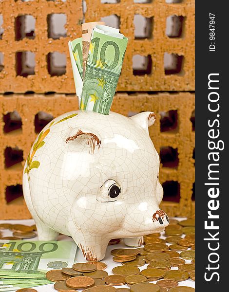 Piggy bank with euros, and bricks in the background