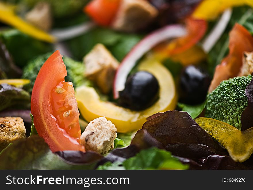 A healthy salad made up of lettuce, tomato, peppers, olives croutons and onion.