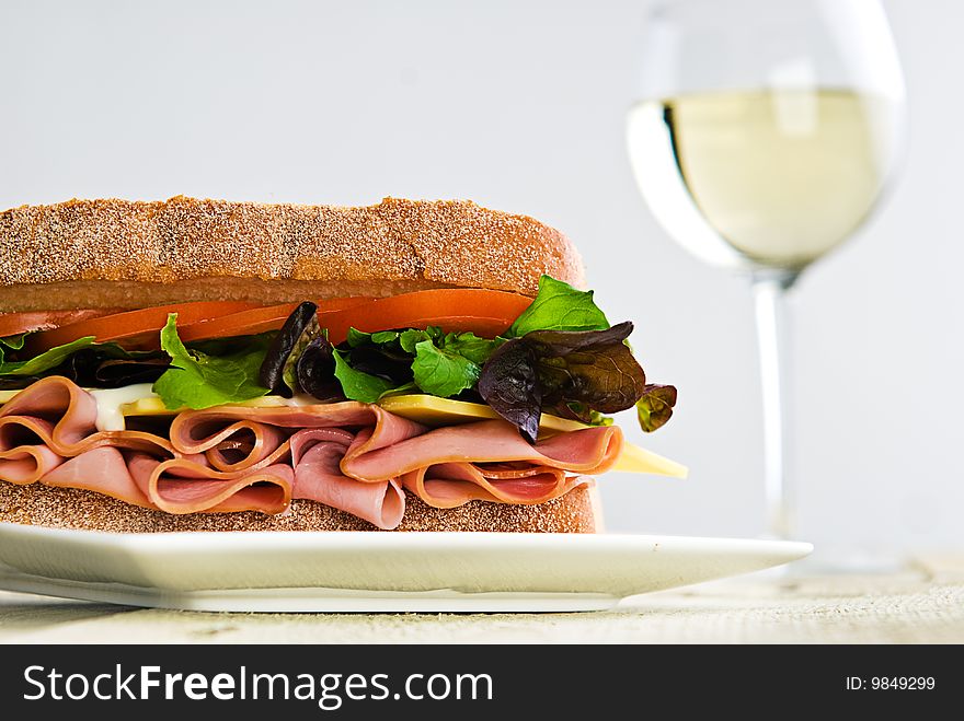A gourmet sandwich with a glass of wine in the background.