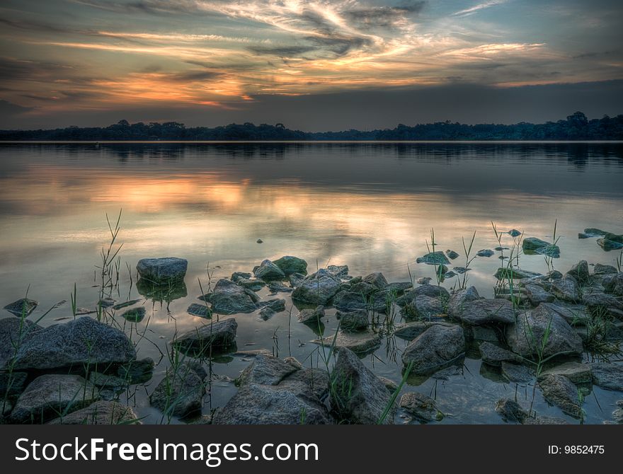 Granite boulders strewn shore of a reservoir seen at sunset
