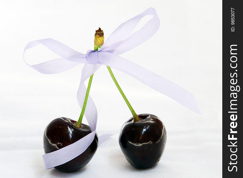 Cherry with a ribbon bow on white background. Cherry with a ribbon bow on white background