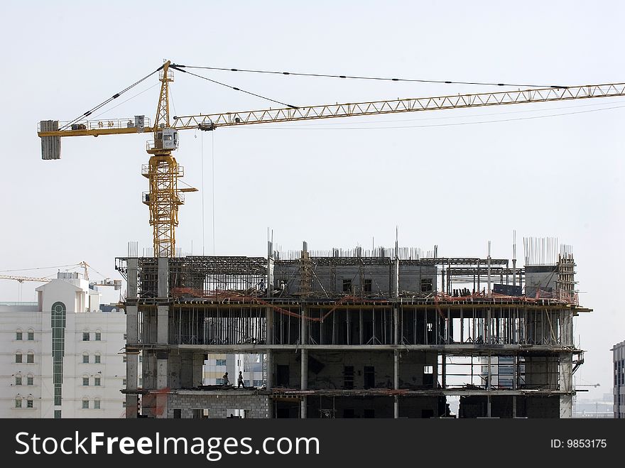 A construction site with a yellow crane on top.