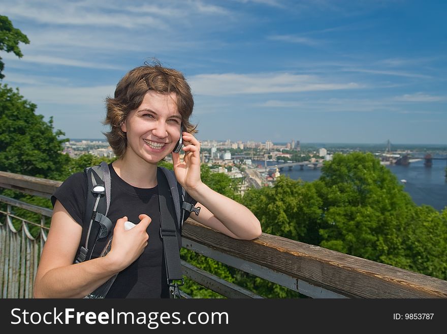 Young woman smiling and talking on the phone at beautiful backdrop of the city of Kyiv. Young woman smiling and talking on the phone at beautiful backdrop of the city of Kyiv