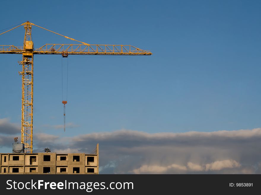 Hoisting crane on the background of gloomy thunder clouds, with copyspace. Hoisting crane on the background of gloomy thunder clouds, with copyspace