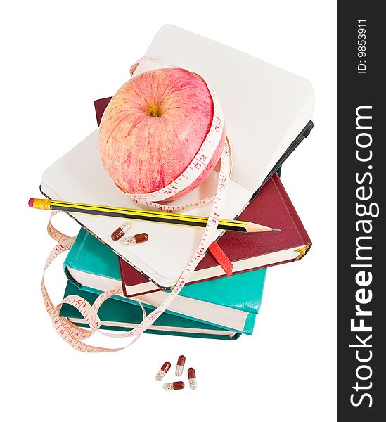 Big ripe apple with measure tape and pills on pile of books as metaphor of healthy eating and diet. Big ripe apple with measure tape and pills on pile of books as metaphor of healthy eating and diet