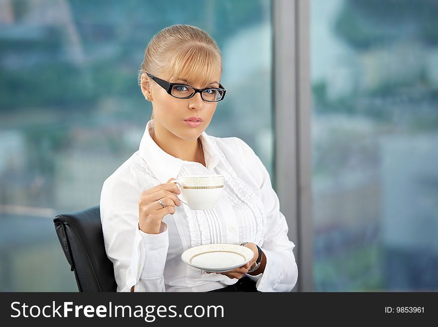 The beautiful business woman with a coffee cup in a hand at office. The beautiful business woman with a coffee cup in a hand at office