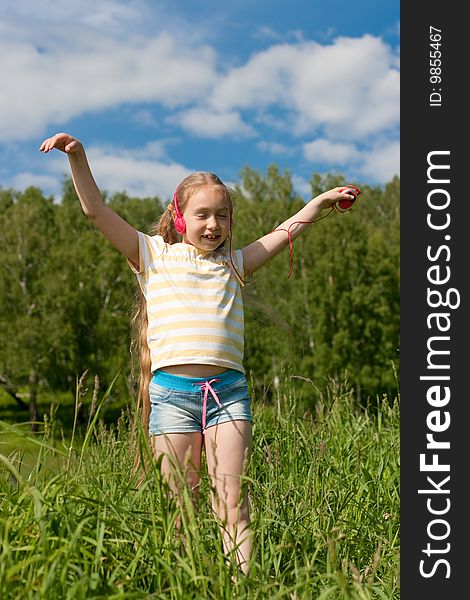 Blonde little girl with closed eyes in red earphones is listening mp3 player music and dancing. Blonde little girl with closed eyes in red earphones is listening mp3 player music and dancing