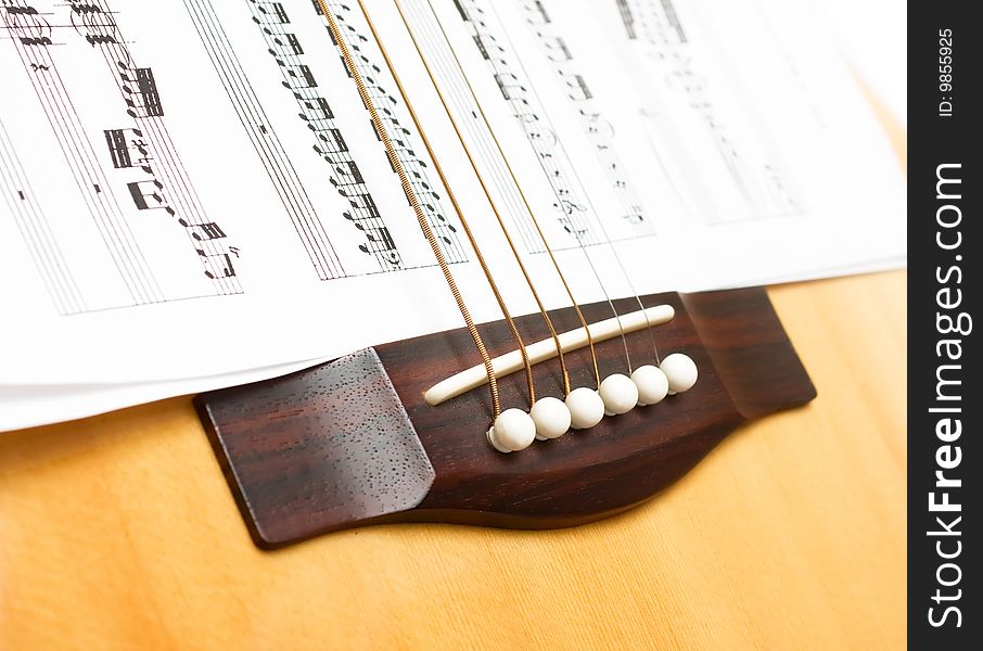 Wooden guitar with six strings on sheets music