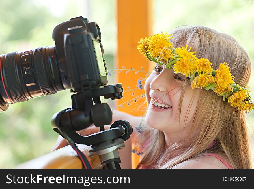 Beautiful girl in a wreath looks in a camera's display. Beautiful girl in a wreath looks in a camera's display