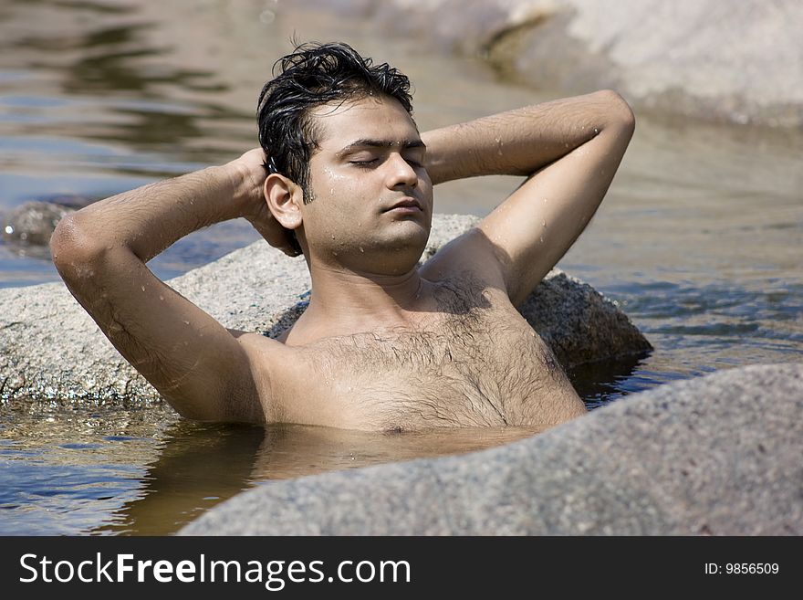 Man having yoga in water between stones