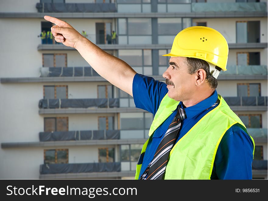 Single mature architect man pointing on site and looking up,construction with workers in background,check out. Single mature architect man pointing on site and looking up,construction with workers in background,check out