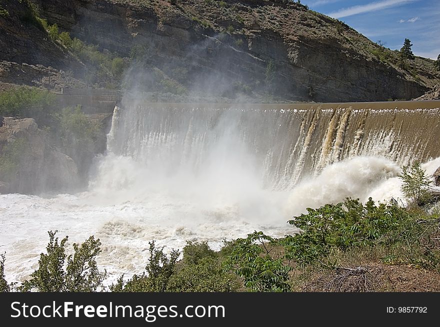 Photo of Enlow Dam in Washington state with desert type mountain, the muddy river going over the fall and mist rising up. Photo of Enlow Dam in Washington state with desert type mountain, the muddy river going over the fall and mist rising up.