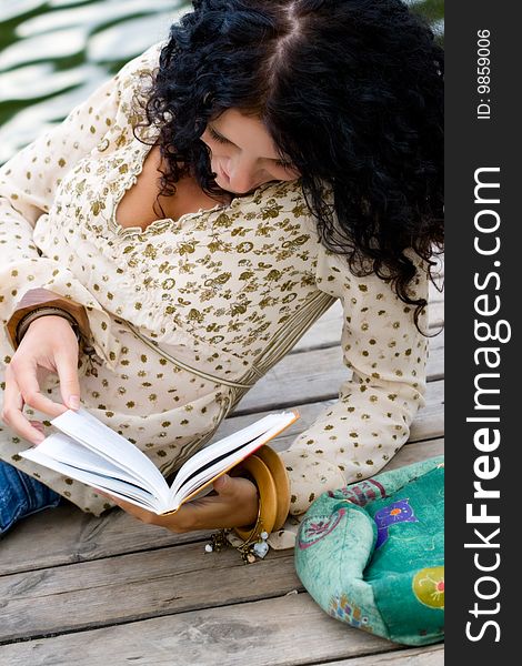 Outdoor portrait of a beautiful woman reading a book