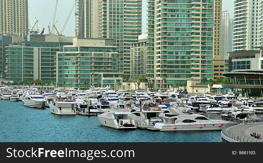 Several boats and yachts berthed in the Dubai Marina with luxury apartments in the background. Several boats and yachts berthed in the Dubai Marina with luxury apartments in the background