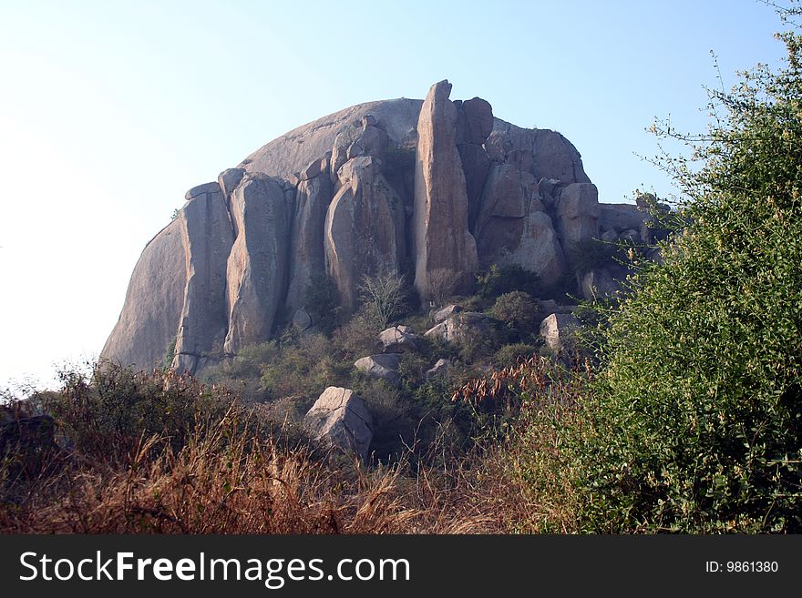 Huge rock with human-shaped rocky figurines in the front. Huge rock with human-shaped rocky figurines in the front