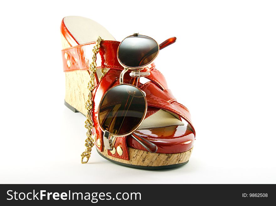 Single red shoe with brown sunglasses and gold bracelet with clipping path on a white background. Single red shoe with brown sunglasses and gold bracelet with clipping path on a white background