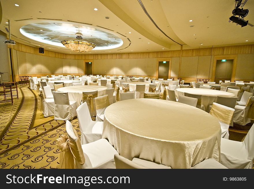 A luxurious banquet room being prepared for an upcoming event, filled with tables and chairs.