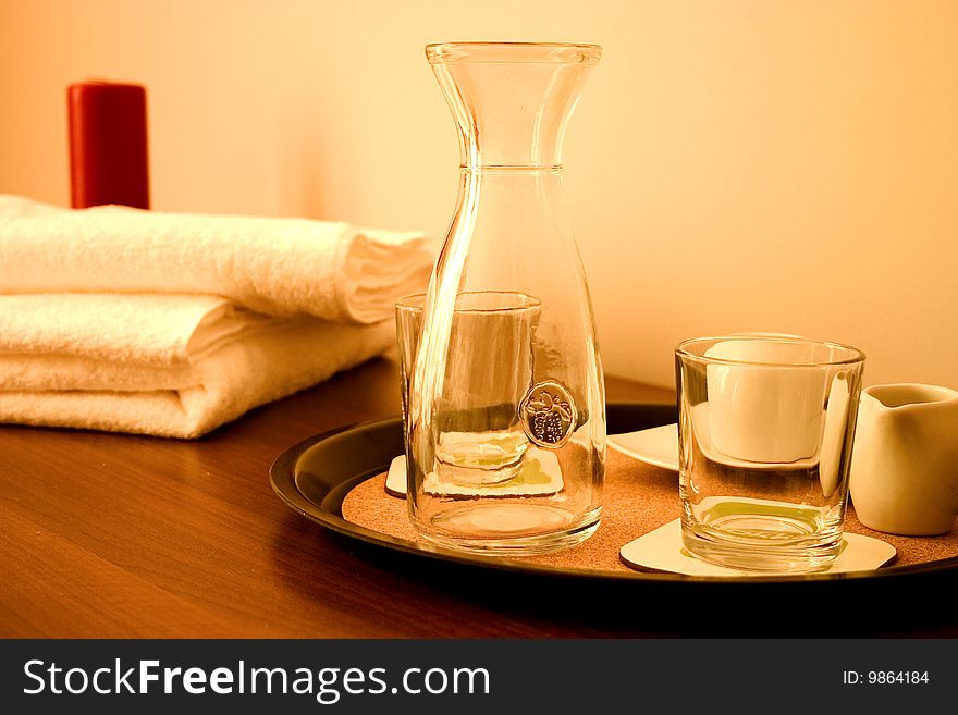 Closeup of nightstand with two red candle, towel and glasses.