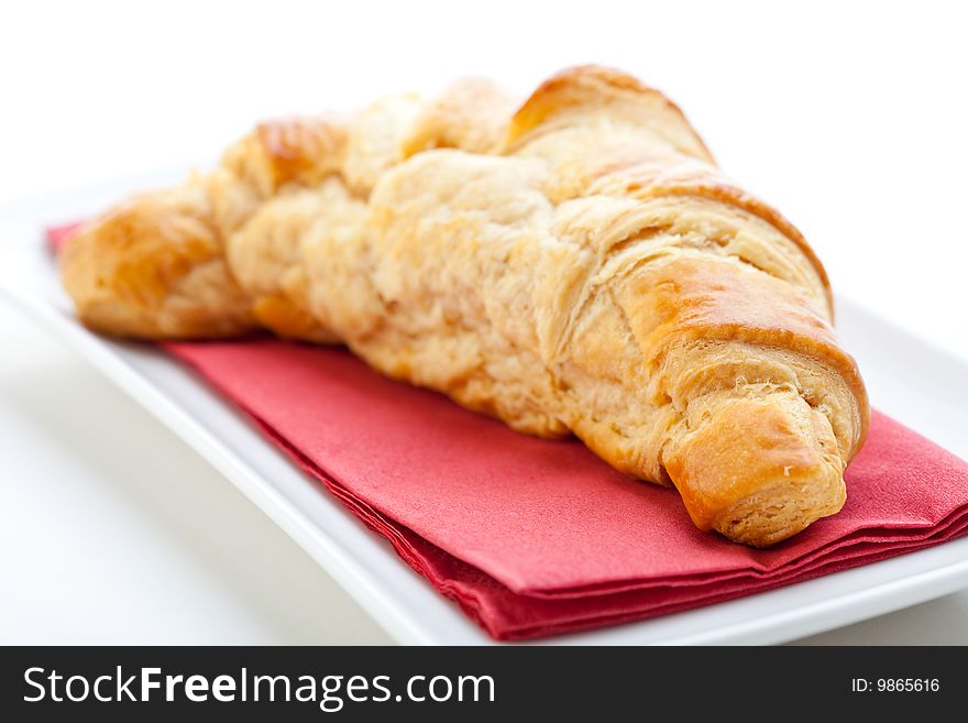 Delicious freshly baked croissant on a white plate with a red napkin