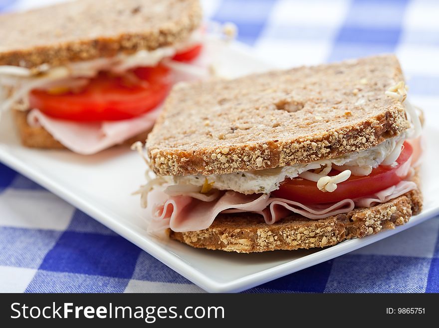 Healthy ham, cheese and tomato sandwich on a white plate
