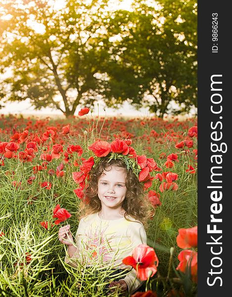 Smiling little girl with flowers in the poppy field at sunset. Smiling little girl with flowers in the poppy field at sunset