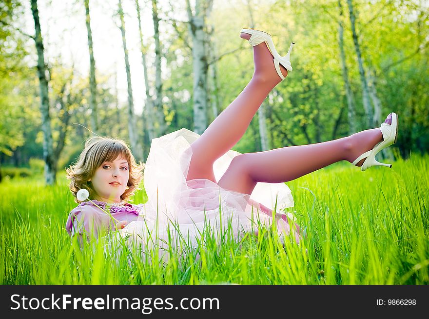 Beautiful girl with dandelion in perfect green grass