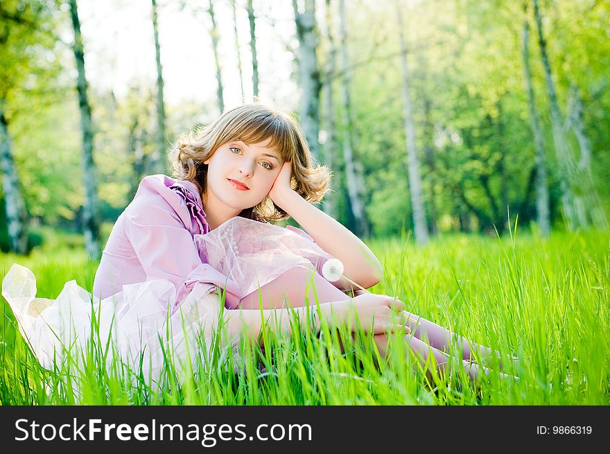 Attractive girl with dandelion in perfect green grass
