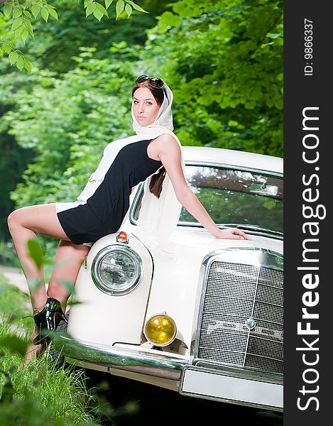 Beautiful pin-up girl sitting on retro car