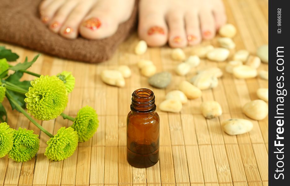 Bottle of aromatic oil, stones and female legs