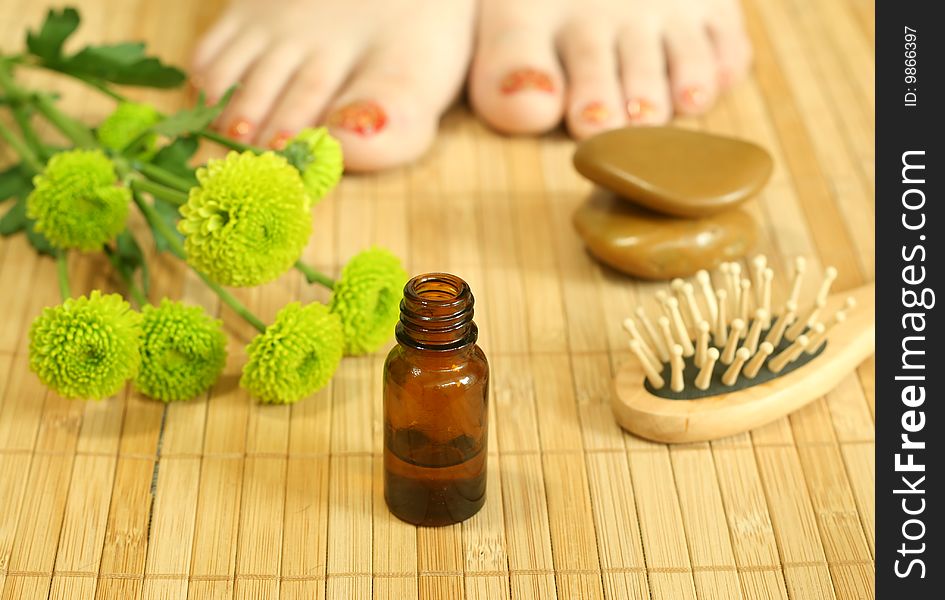 Bottle of massage oil, stones and female legs. Bottle of massage oil, stones and female legs