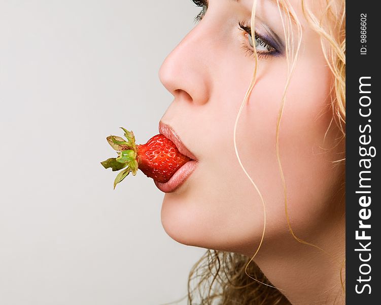 Pretty female model eating tasty strawberry