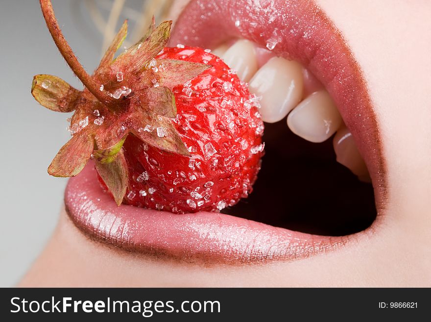 Pretty female model eating tasty strawberry