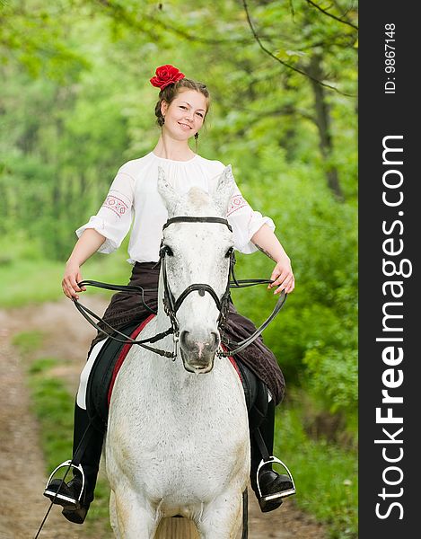 Smiling girl riding horse in the forest