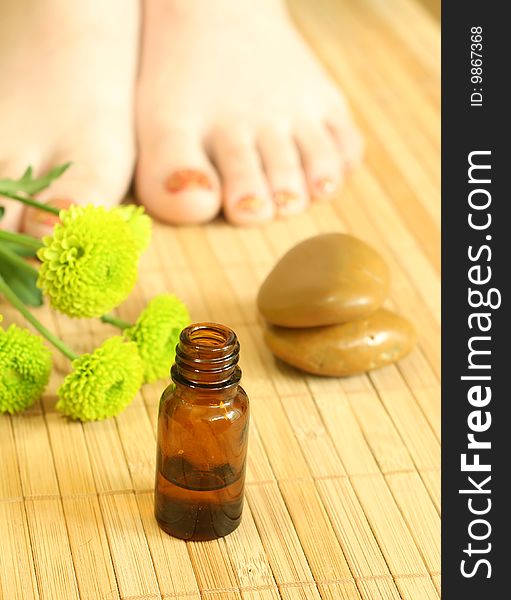 Bottle of massage oil, stones and female legs. Bottle of massage oil, stones and female legs