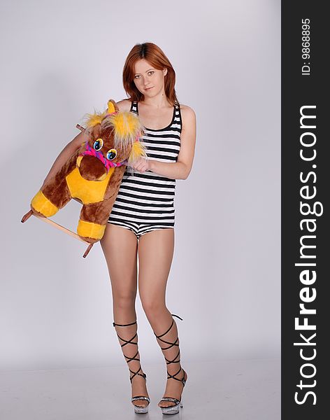 Girl with toy, horse, striped clothing. Girl with toy, horse, striped clothing