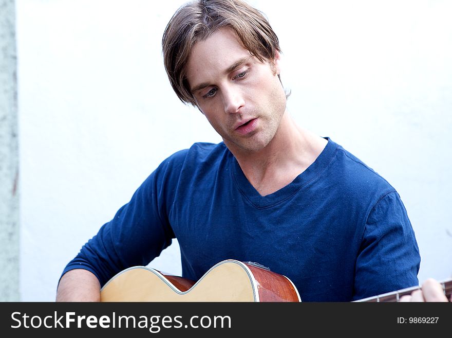 An attractive guitar player with a blue shirt and white backround