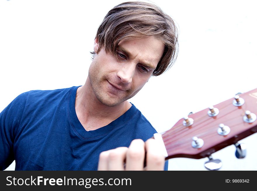 An attractive guitar player with a blue shirt and white background