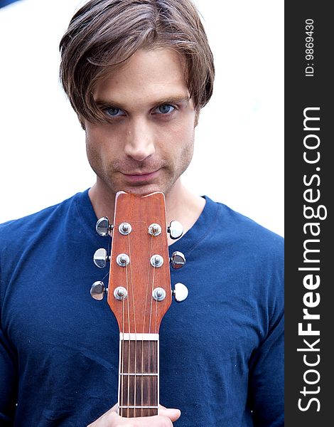 An attractive guitar player with a blue shirt and white backround